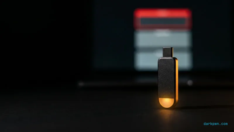 A hardware security key on a black workbench beside a screen showing a segmented token, one segment edged in red