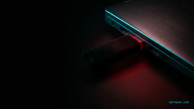 A USB device inserted into a generic laptop port glowing red on a dark desk with cyan accents
